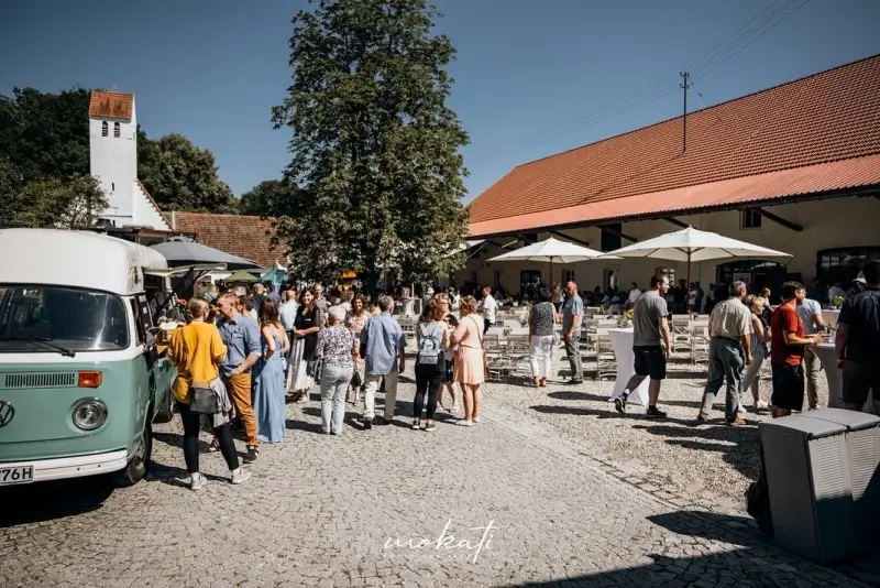 Corporate event in the courtyard of Hofgut Sickertshofen during the day, with a food truck and guests